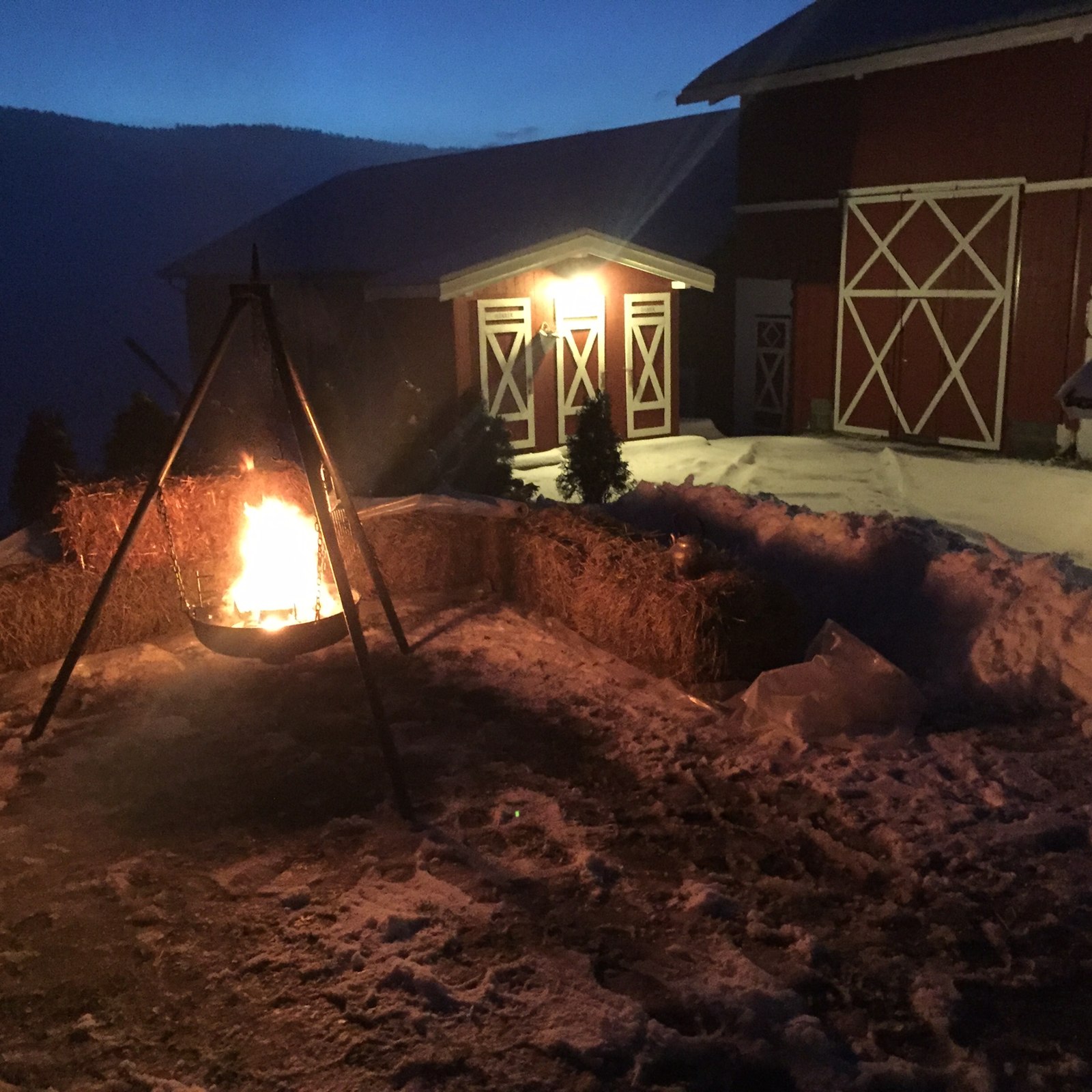 Låven på Solum i skumringen, med lys i vinduene og bål utenfor